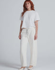 ASKK Cancun relaxed barrel sweatpants in white styled with tee and heels, minimal studio backdrop, modern look.
