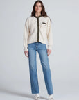 ASKK Greenwich Cardigan with green trim styled with blue jeans and white shoes, modern casual look.