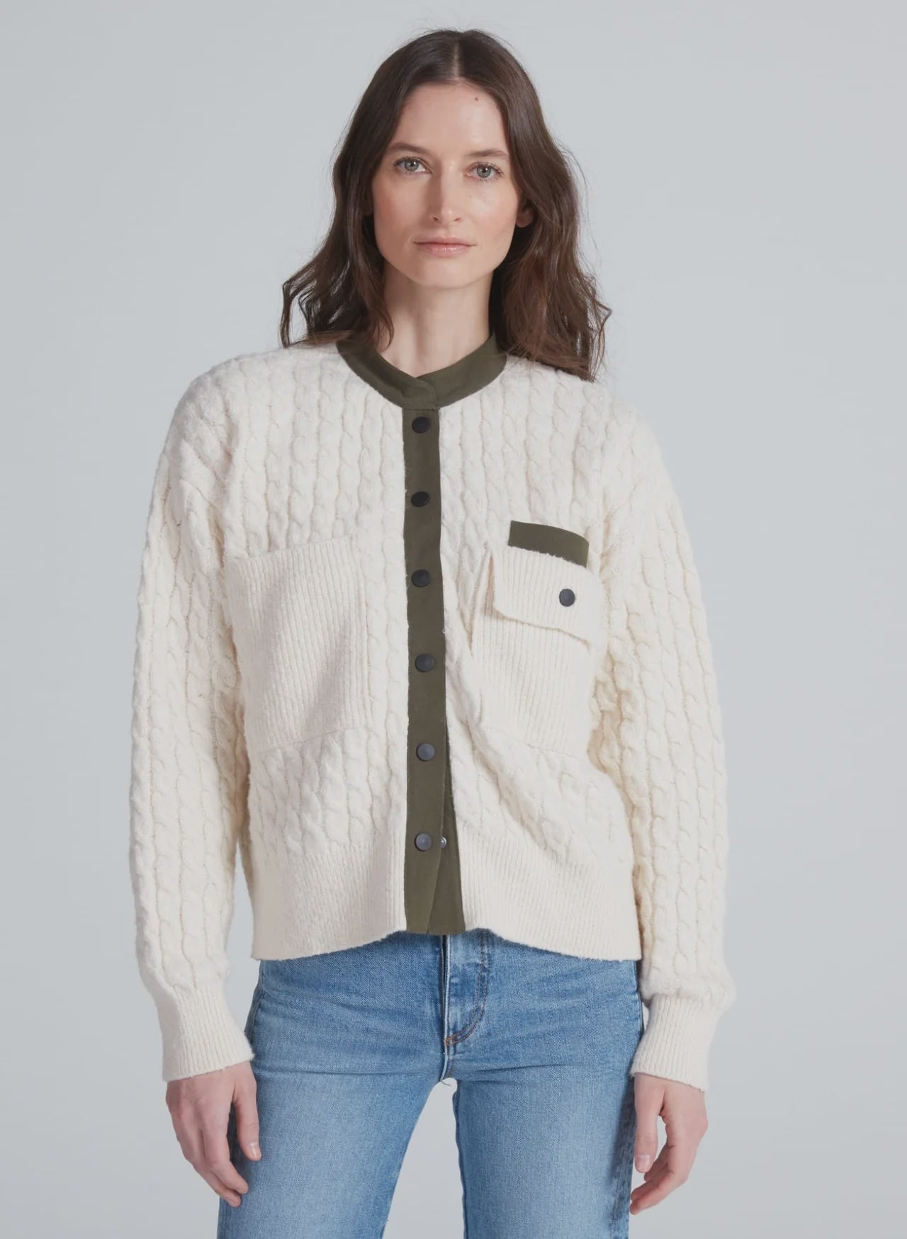 ASKK Greenwich Cardigan in cream cable knit, styled with a green shirt and blue jeans for a relaxed, cozy look.