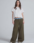 ASKK high-rise olive Greenwich Pant with denim waist, styled with a white crop tee and white shoes, modern casual look.