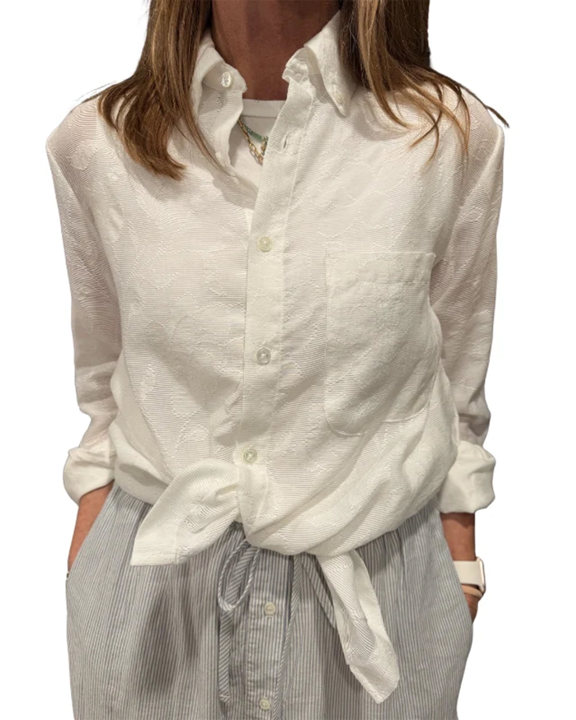 The ATELIER Shirt by Cissa tied at the waist, paired with gray striped pants, styled for a relaxed modern look.