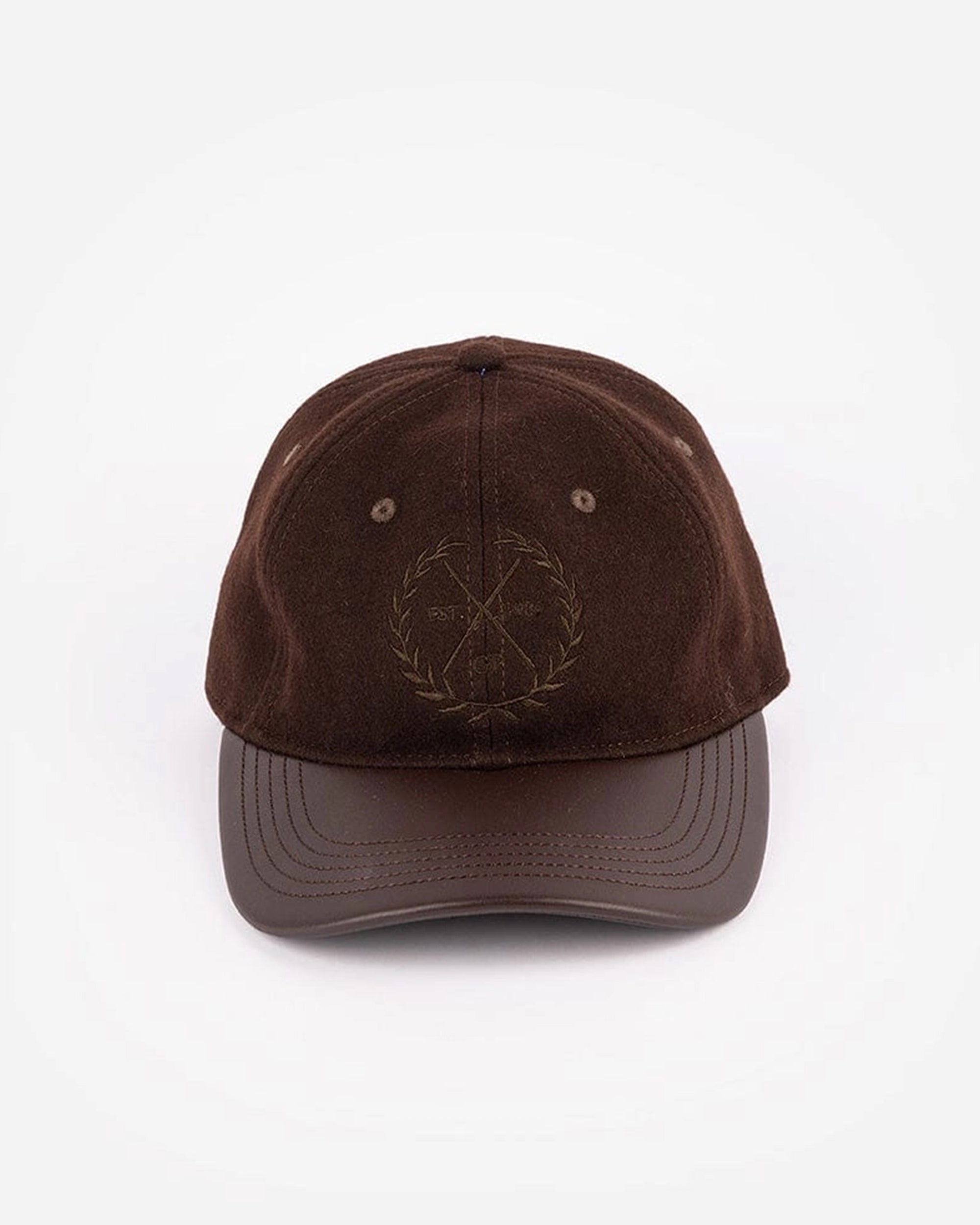 The Faire Aven Leather Ball Cap features a curved brim, subtle crossed golf clubs and laurel wreath embroidery, and an adjustable strap—an ideal winter accessory shown against a plain white background.