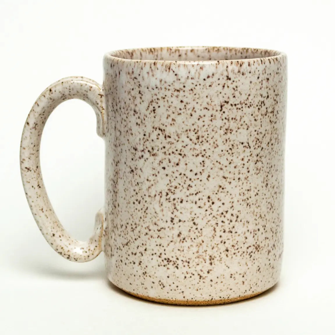The Faire Ceramic Mug features a large handle and speckled beige and brown glaze. Handmade, dishwasher safe, and ideal for everyday use, it’s shown against a plain white background.