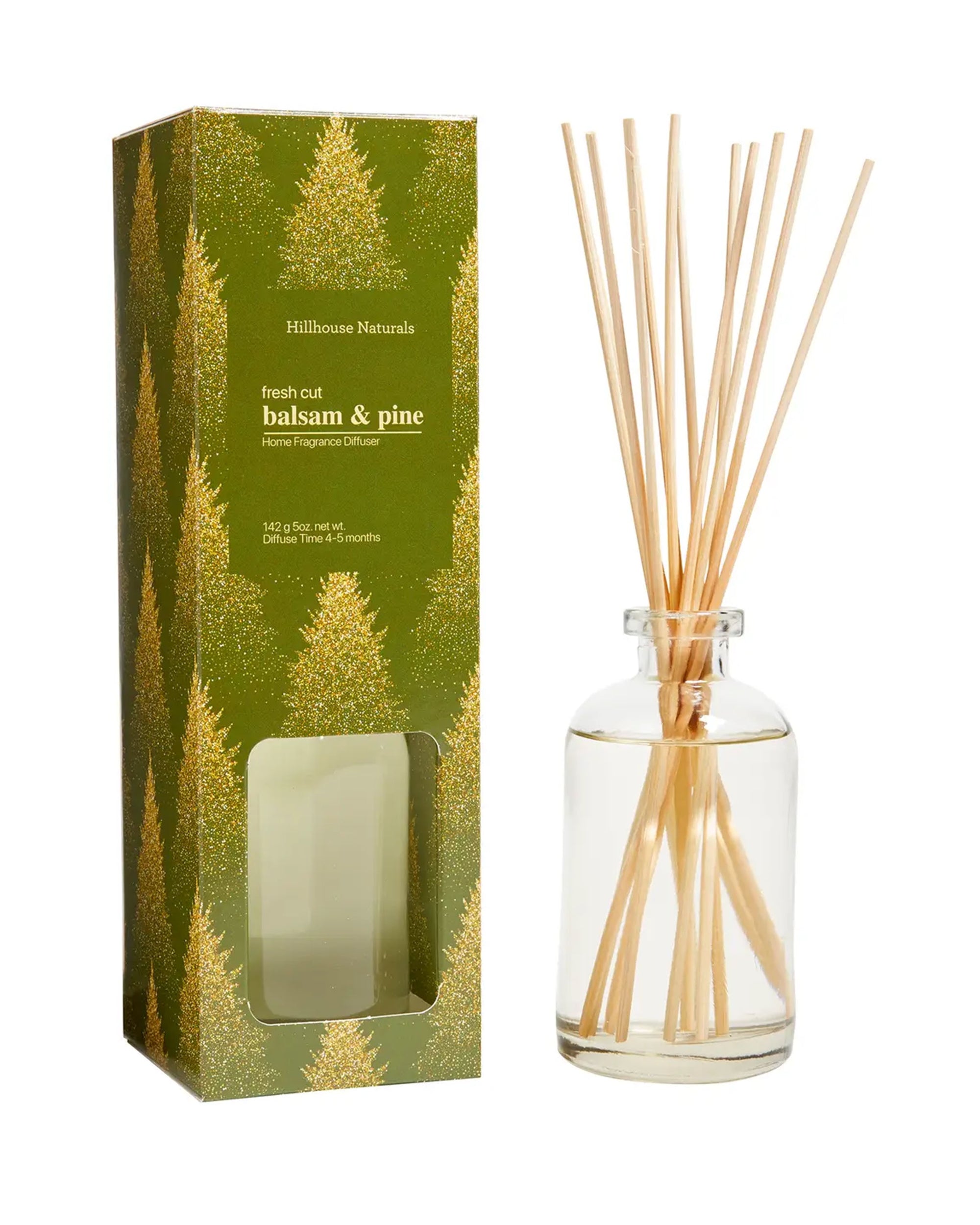 A glass Faire Diffuser Balsam & Pine with wooden sticks sits next to a green box featuring gold pine tree graphics and labeled “fresh cut balsam & pine.”.
