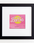 A framed Barbie board game titled "California Dream," prominently displaying a pink box with yellow accents, mounted on a white acrylic background within a Match South Art Square Black Frame.