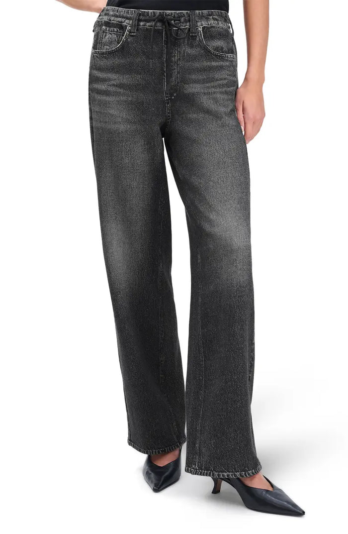 A person wears Rag & Bone's miramar terry drwcrd wide pant—high-waisted, loose-fit, black washed pants with an elastic waist and front pockets—paired with black pointed-toe heels. The cropped photo highlights the pants and shoes.
