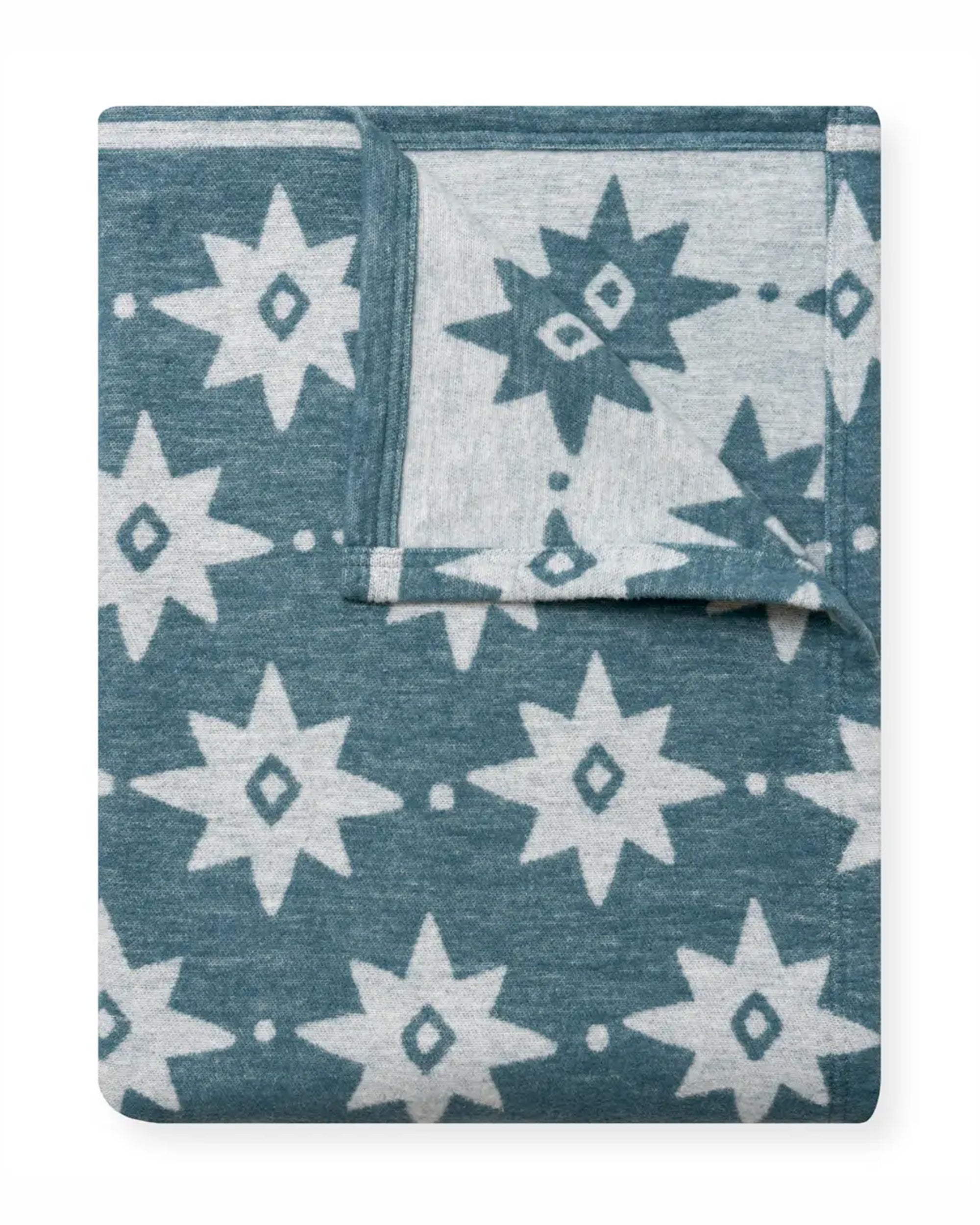 The Faire Big Sky Lightweight Blanket is shown folded, featuring a blue background with a white geometric star and diamond pattern, displaying both the front and back sides of the fabric.