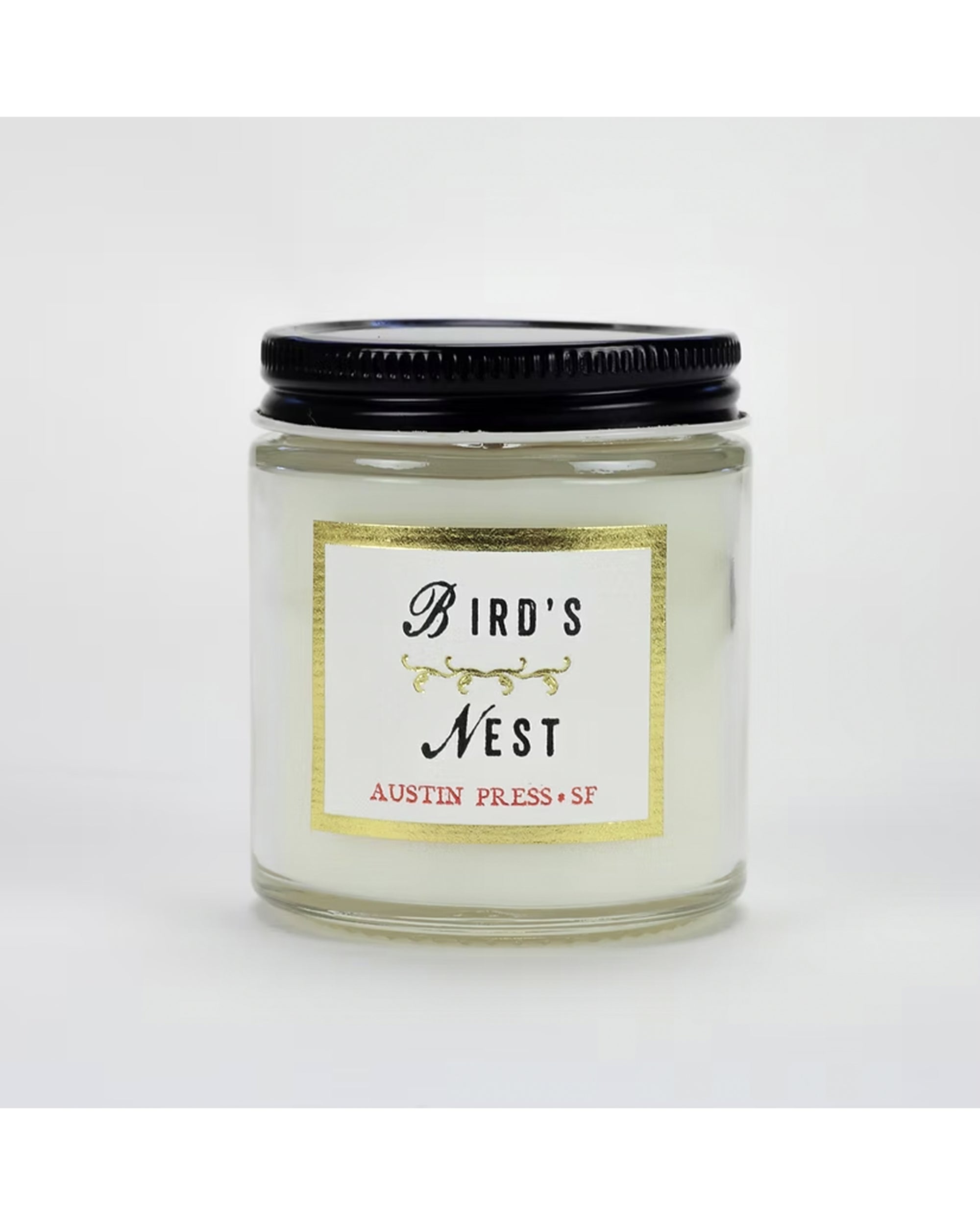 The Austin Press Travel Candle by Faire is a clear glass jar candle with a black lid and white label featuring gold and black decorative text, crafted from botanical waxes for an all-natural experience.