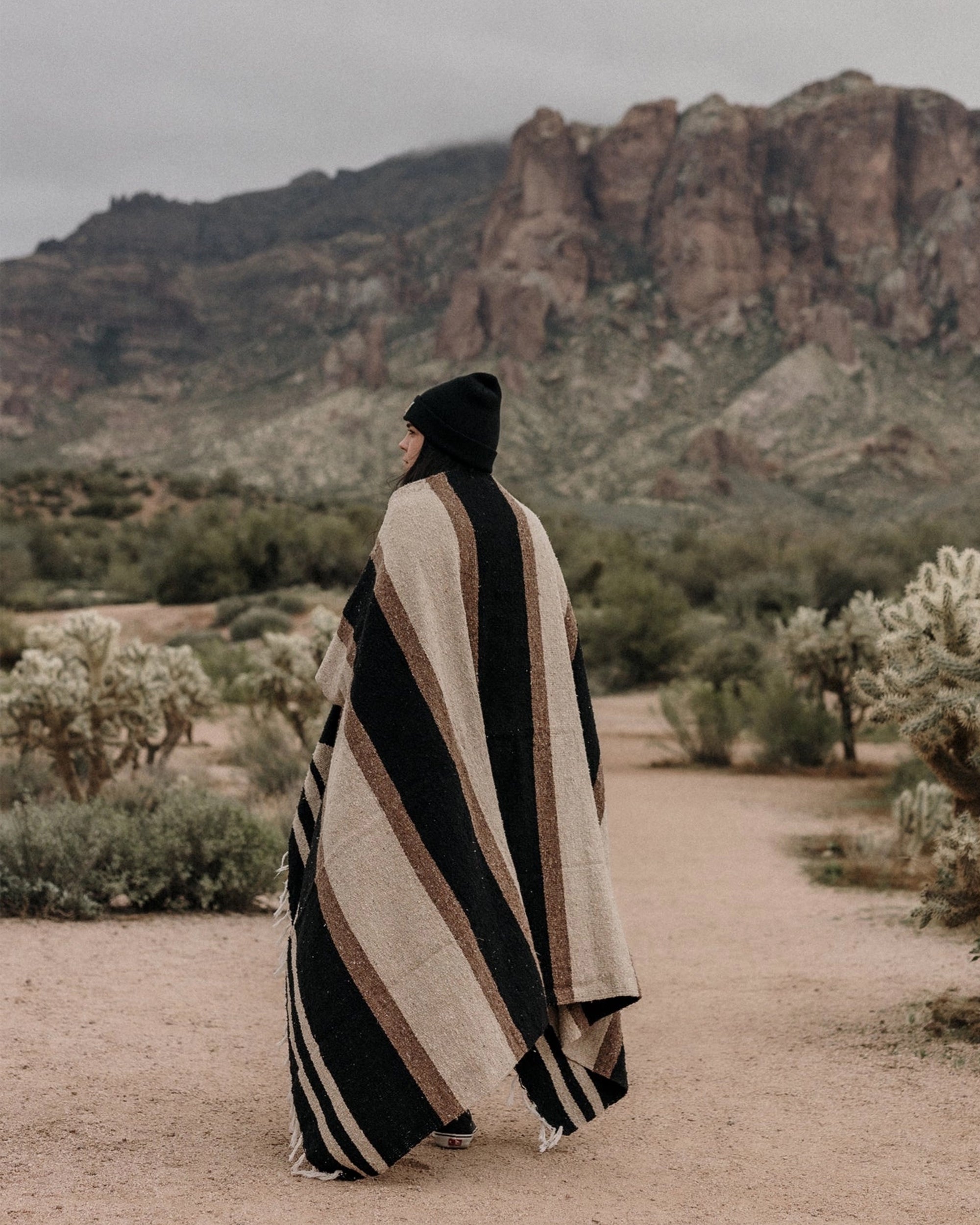 Faire Blackstone Lines handwoven blanket in black and white, styled on a person outdoors along a desert path.