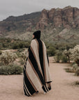 Faire Blackstone Lines handwoven blanket in black and white, styled on a person outdoors along a desert path.