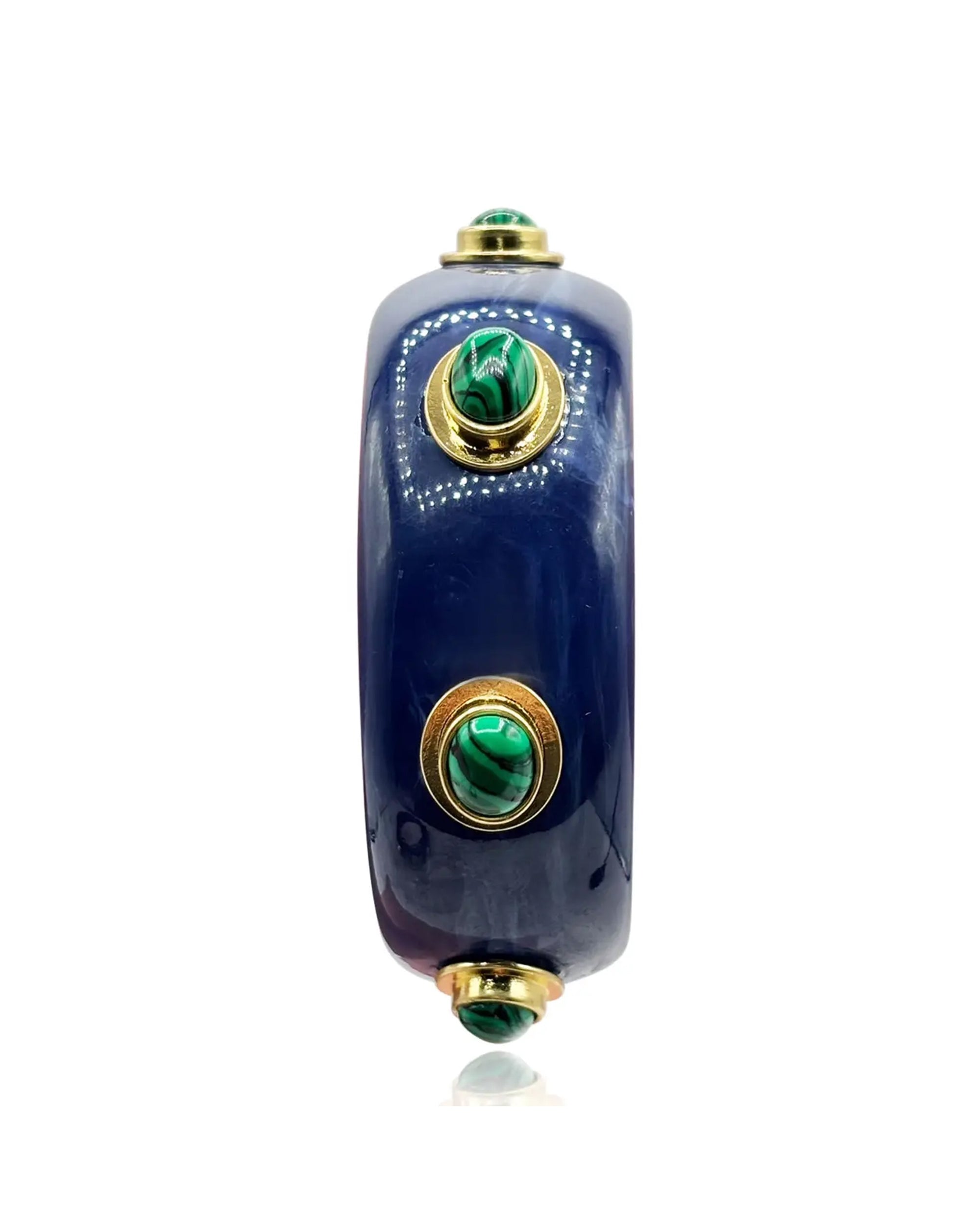 The Faire Renee Bangle in lapis resin features three evenly spaced round malachite stones set in gold bezels on a wide, glossy dark blue surface.