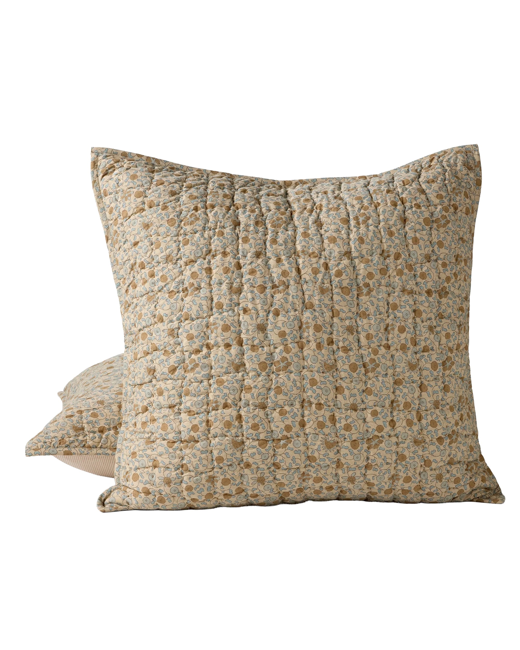 The Blossom Hand Stitched Euro Sham by Coyuchi Inc features two square quilted pillows in organic cotton with a vintage Sarasa print on light beige and handstitched wave quilting, showcasing tan, yellow, and muted green floral patterns. One pillow is placed behind the other.