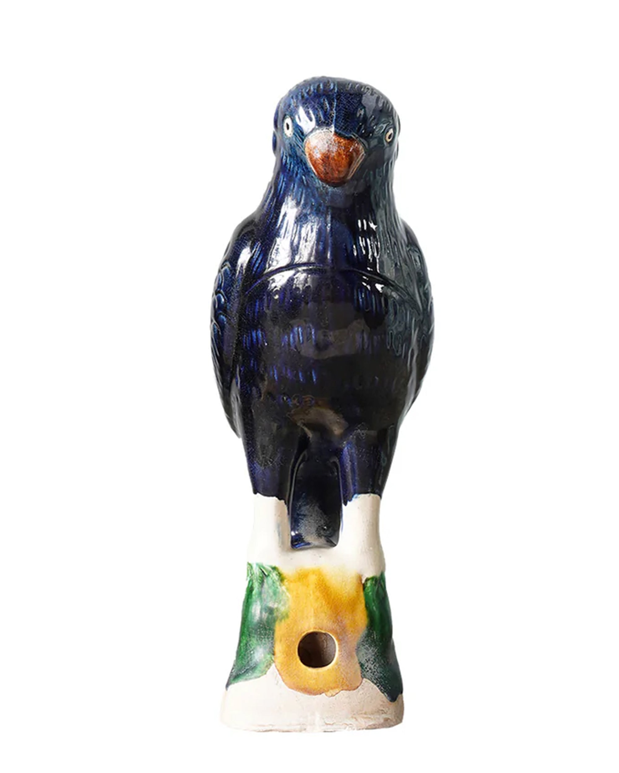 The Parrot Small by Blue Ocean Traders is a ceramic bird whistle shaped and painted like a dark blue bird with an orange beak, perched on a green and white base, inspired by Jingdezhen hand-painted porcelain craftsmanship.