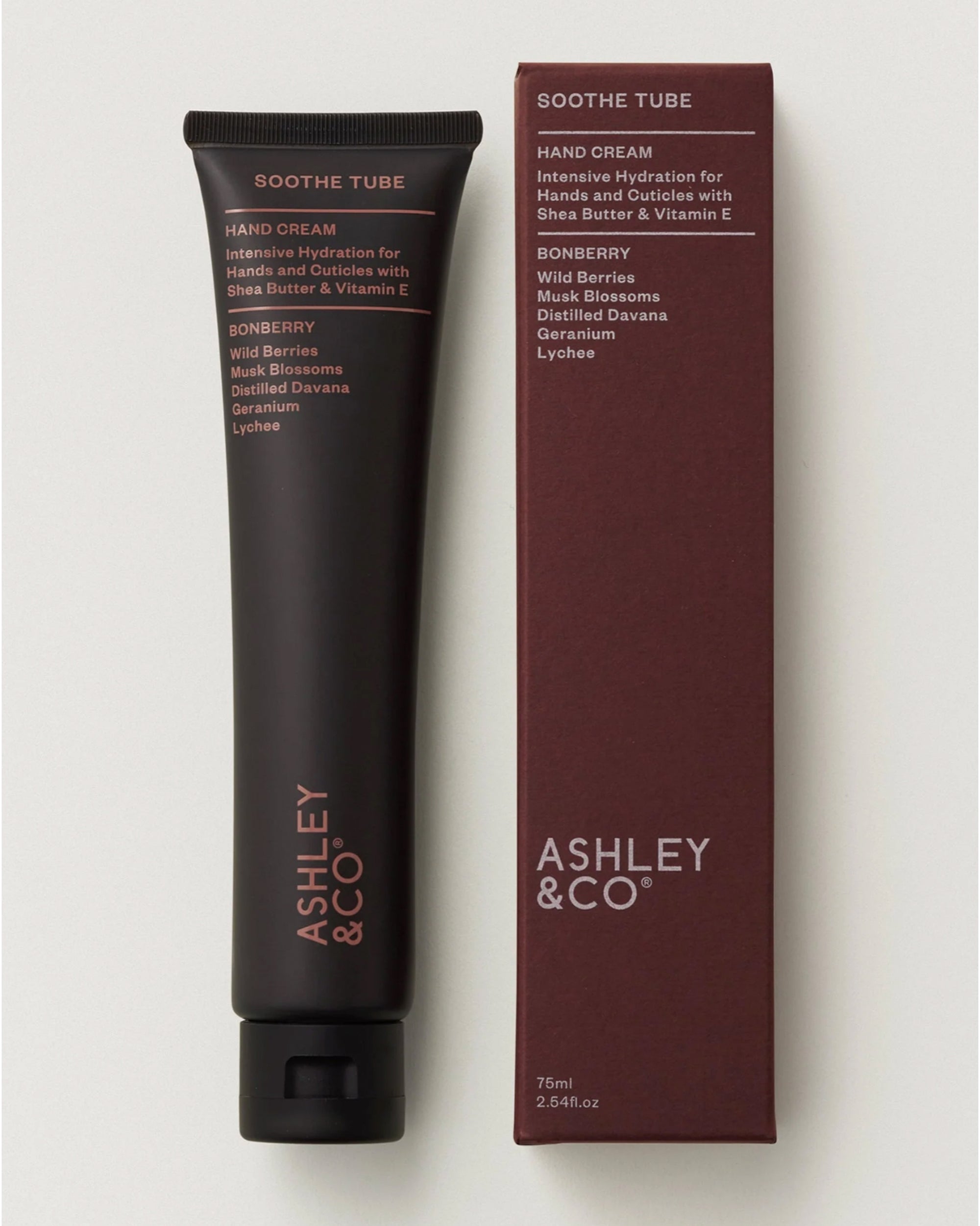 A black tube labeled "Ashley & Co Soothe Tube Hand Cream" stands beside its maroon box, featuring shea butter, Vitamin E, and a bonberry scent with wild berries, musk blossoms, geranium, and lychee.