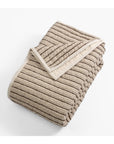 The Amity Home Bonita Quilt King features beige and brown stripes with a soft high-low texture. Displayed folded on a white background, one corner is turned to reveal its cozy linen-cotton underside.