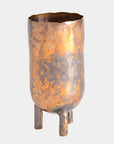 The Alchemy Container Burnt Brass T by Global Views is a handcrafted brass vessel with a hammered, mottled surface, uneven rim, round body, and three short legs—a distinctive piece from the Alchemy Container Collection.