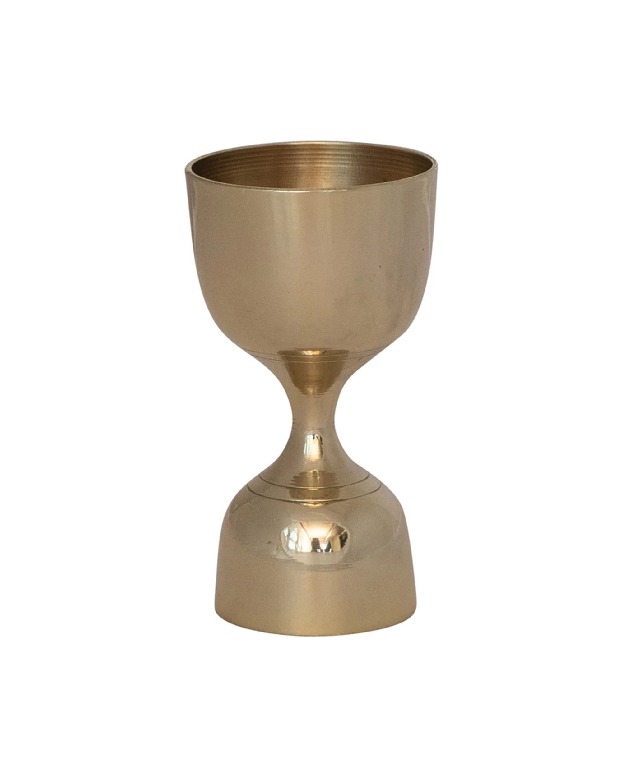 The Creative Co-op Brass Double Sided Cocktail Jigger, with an hourglass shape, wide cup, and flared base, gleams gold against a plain white background.