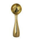 A single, elegant Sir/Madam Brass Dessert Scoop isolated on a white background, viewed from the front with light reflections on its surface, reminiscent of a bungalow-style accent in Scottsdale, Arizona.