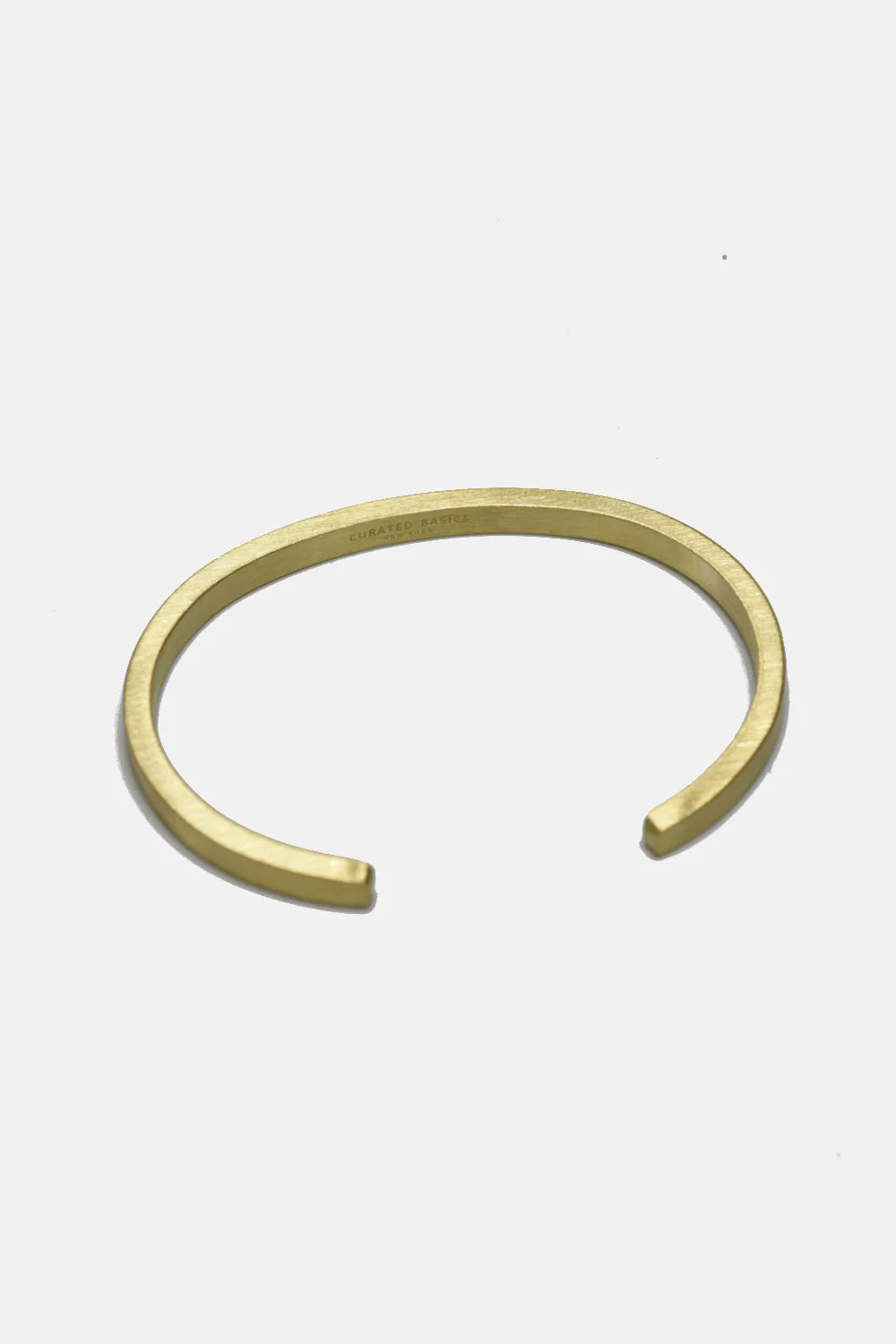 The MENS Flat Cuff by Curated Basics is an open-ended brass bracelet displayed on a plain white background—an elegant accessory that adds a touch of modern style to any outfit.