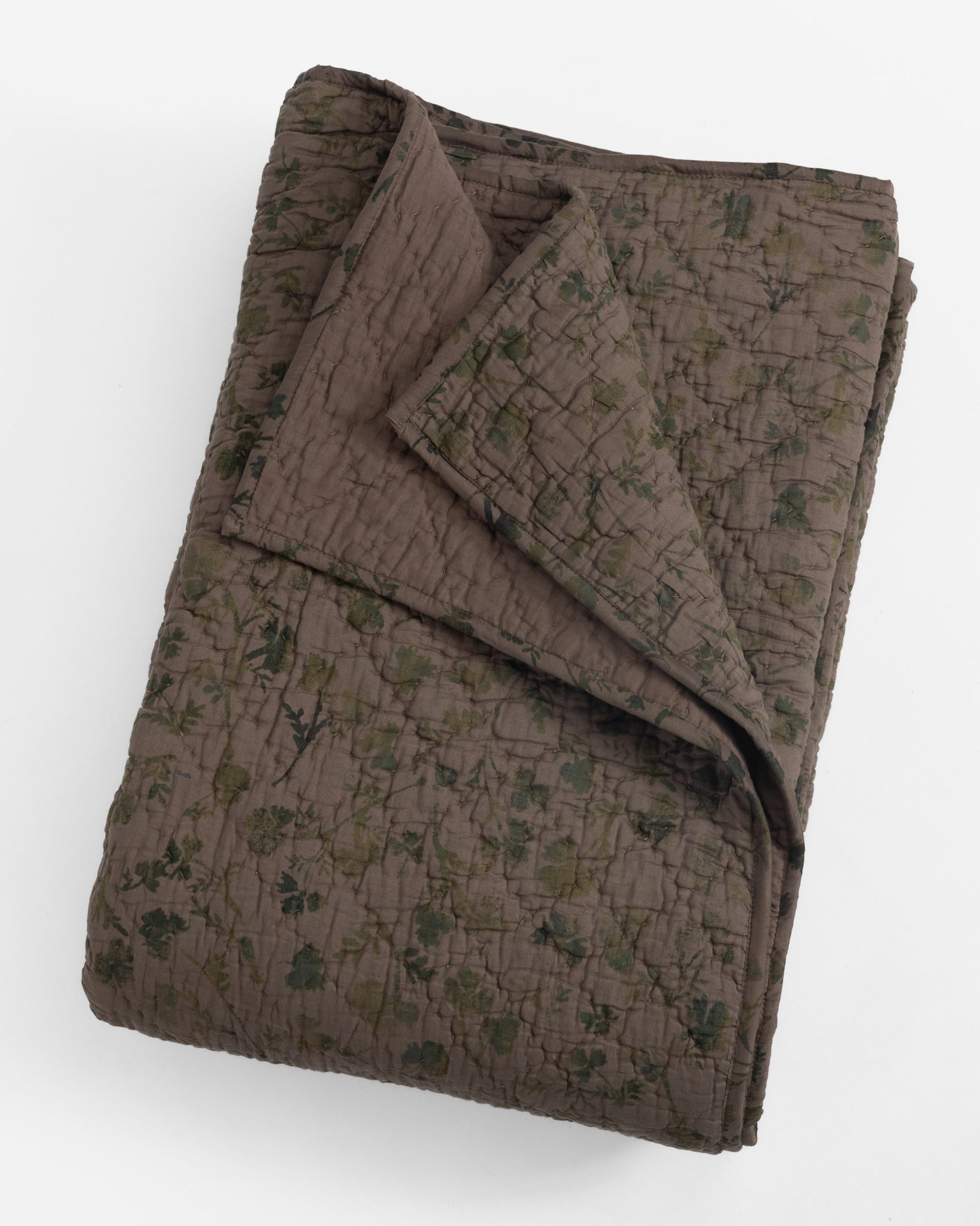 The Brittany Quilt by Amity Home is a folded, hand-quilted blanket featuring a subtle dark floral pattern on a brown background, crafted in an heirloom-inspired style and displayed on a white surface.