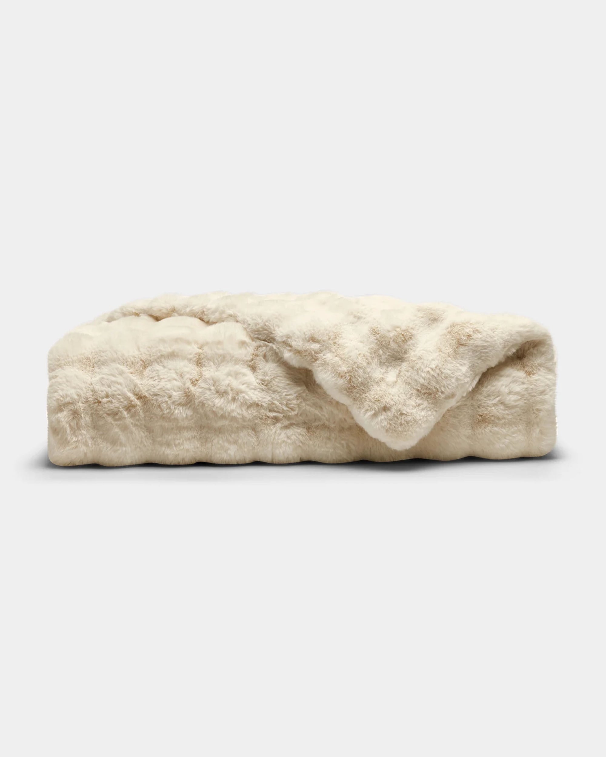 The Cozy Earth Bubble Cuddle Blanket, in cream, is folded on a light gray background, highlighting its ultra-soft faux fur texture.