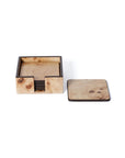 The Zodax Valberg Burl Coaster Set features a square holder with several light wood coasters inside, plus one displayed outside, all showing the natural grain patterns of burl veneer.