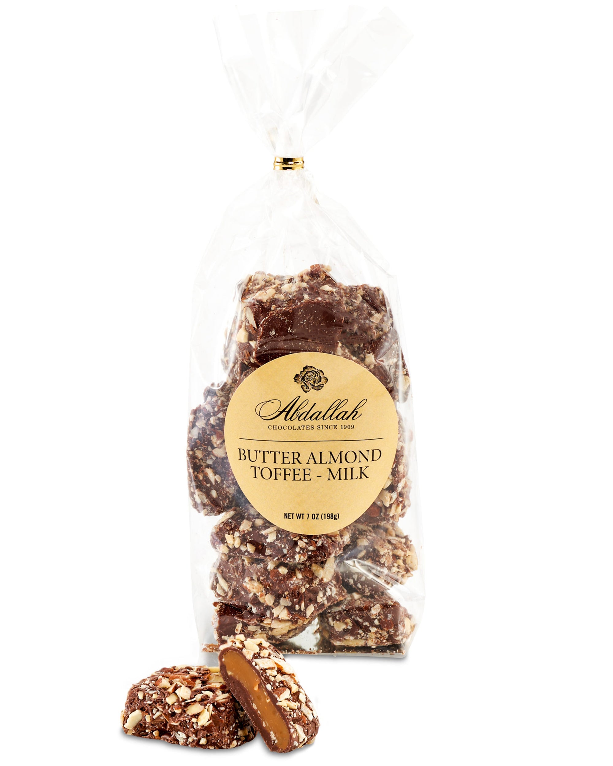 A clear bag labeled "Abdallah Butter Almond Toffee Milk Chocolate" displays milk chocolate-covered toffee coated in chopped almonds. Two toffee pieces are in front, one split open to reveal the crunchy inside.