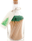 Faire's Glass Bottle Matches come in a glass bottle with green-tipped matches, a cork stopper, and plastic-free packaging. A white tag with a hand-drawn Christmas tree is tied around the neck with twine, perfect for sustainable living.