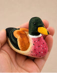 Green hand-painted carved basswood duck figurine by Faire, perfect for rustic decor, shown held in hand.