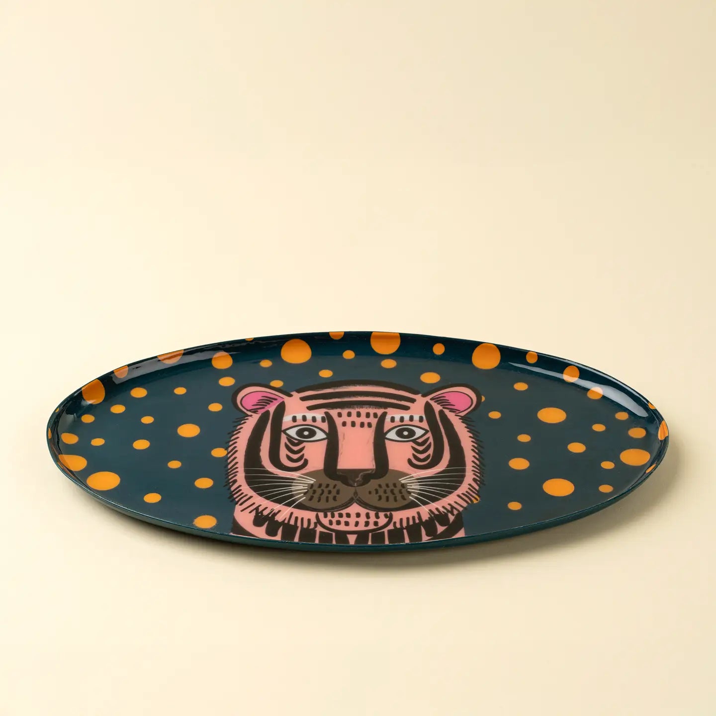 The Tiger Spot Tray by Indaba is an oval accent tray with a dark base, orange spots, and a central pink tiger face—ideal for adding decorative flair to any space.