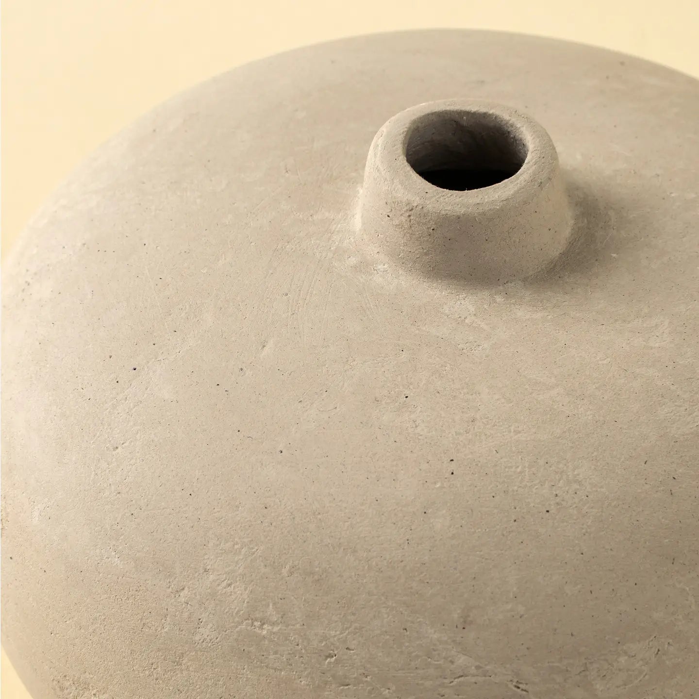 Close-up of the Rotunda Paper Mache Vase by Indaba, featuring a handcrafted beige finish and narrow circular opening. Its matte, textured surface makes this sculptural accent a refined decor piece, shown against a plain light background.