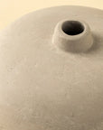 Close-up of the Rotunda Paper Mache Vase by Indaba, featuring a handcrafted beige finish and narrow circular opening. Its matte, textured surface makes this sculptural accent a refined decor piece, shown against a plain light background.