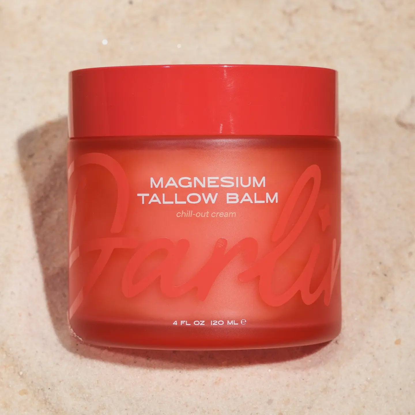 A red jar of Faire's Tallow Face Balm labeled "Chill-Out Cream" rests on a textured surface, offering 4 fl oz (120 mL) of soothing relief. Its large stylized text emphasizes hormonal balance benefits through tallow skincare.