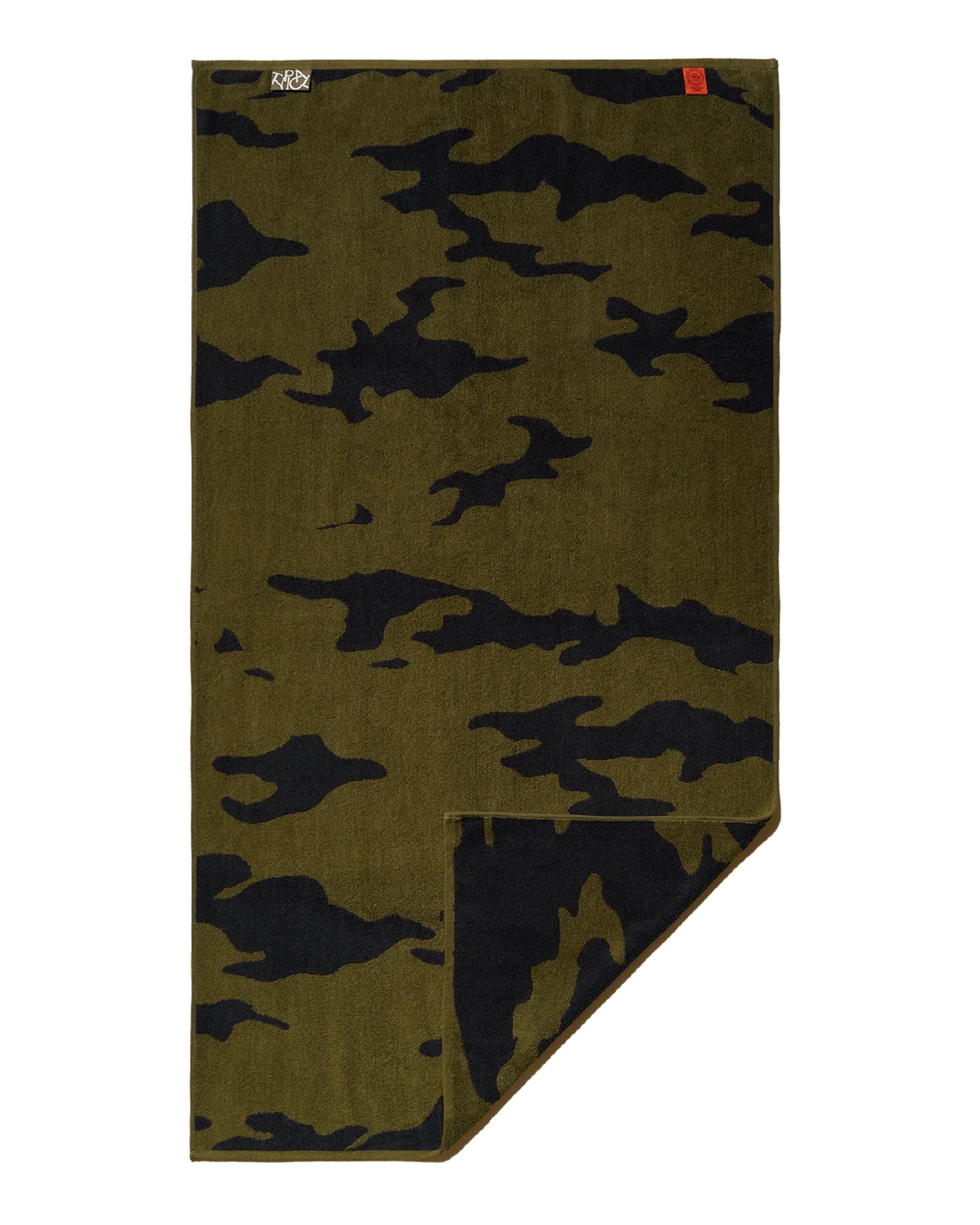 The Wild Camouflage Bath Towel by Typical features a green and black pattern. Rectangular in shape, it is slightly folded at one corner to reveal the reverse side, with small labels visible at the top left and top right.
