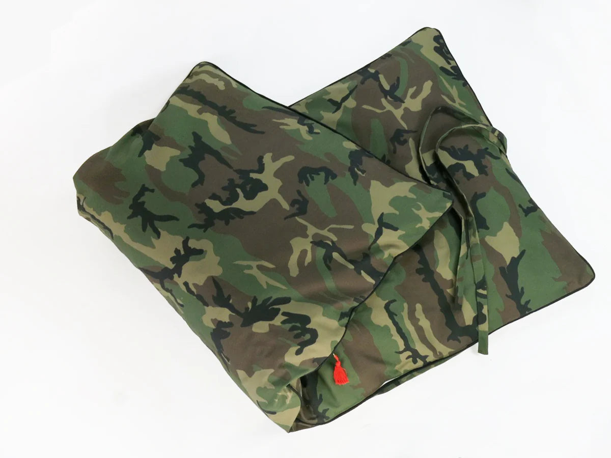 Two Hedgehouse Throwbed pillows with cotton removable covers in a camouflage pattern rest on a white surface, one slightly overlapping the other. A fabric tie is attached to one; both are machine washable for easy care.
