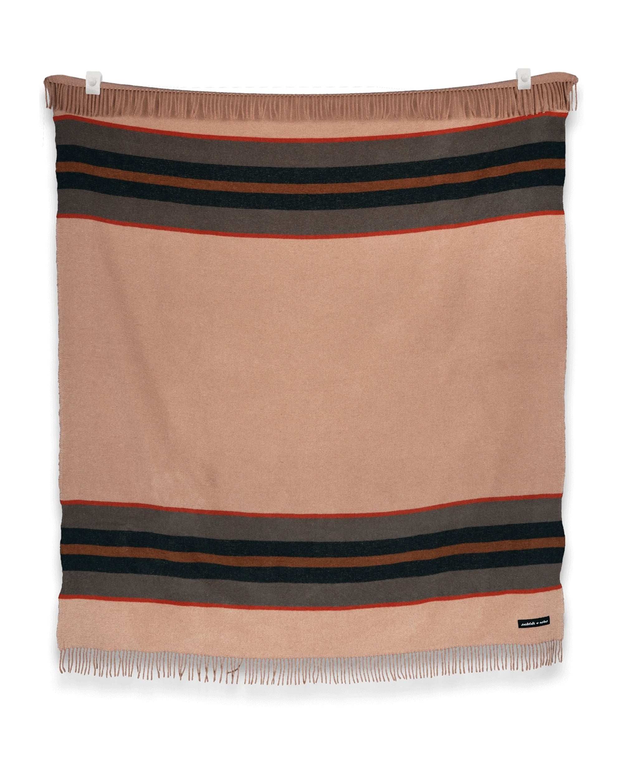 The S&A Blanket by Faire is a vintage-inspired rectangular beige throw with black and red stripes near the top and bottom and fringe detailing, shown laying flat against a white background.