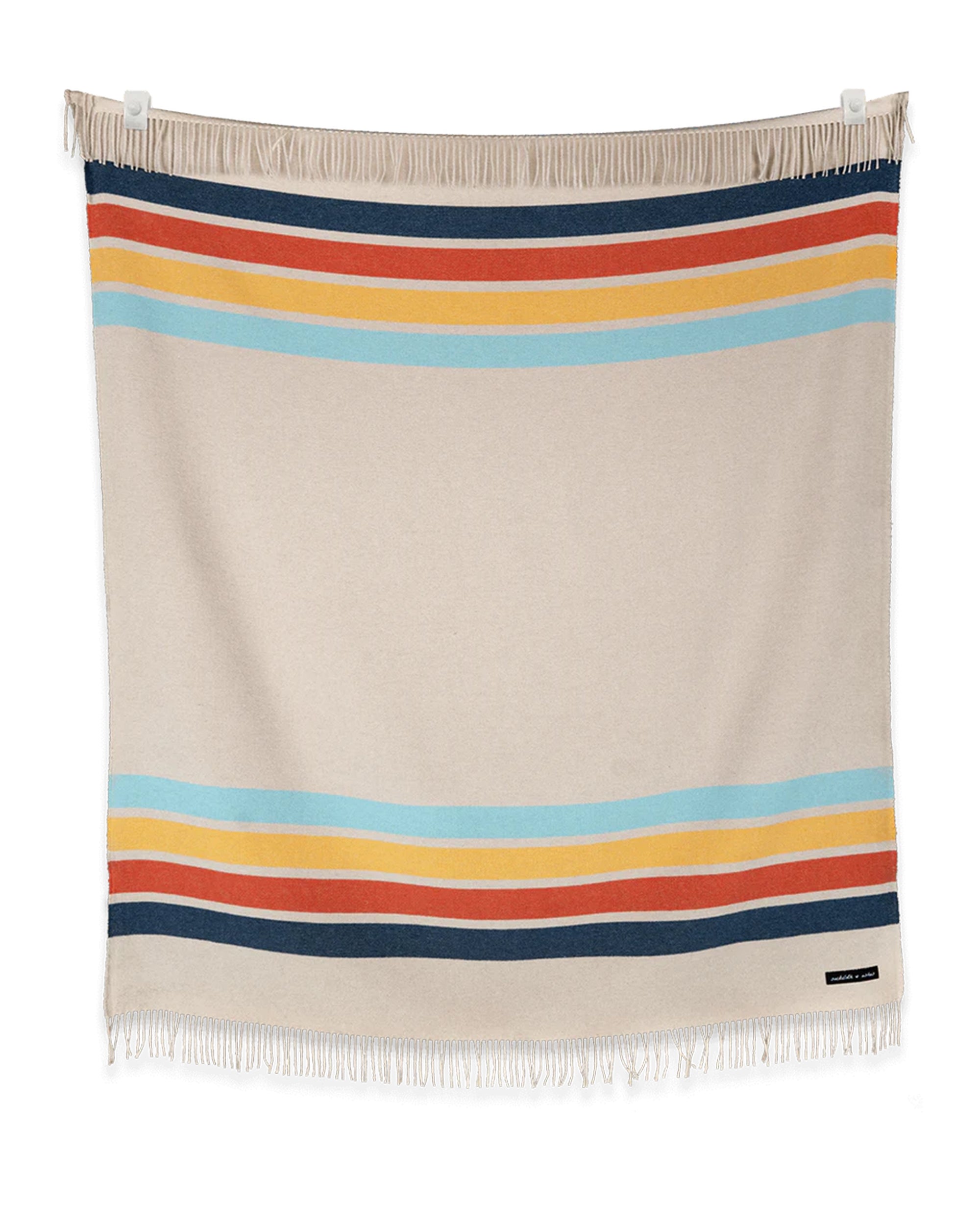 The Sackcloth & Ashes/Camp Coast blanket by Sackcloth & Ashes is a cozy beige wool blend with blue, orange, yellow, and red stripes near the edges and border fringe—perfect for snuggling by the campfire.