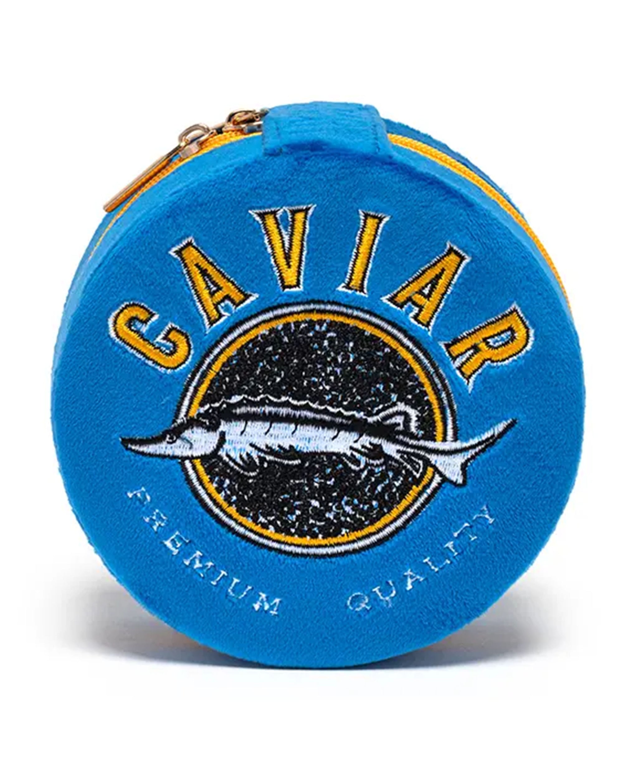 The Caviar Jewelry Case is a round blue velvet organizer with a yellow zipper, featuring an embroidered fish, "CAVIAR" in bold yellow letters above, and "PREMIUM QUALITY" in white below.