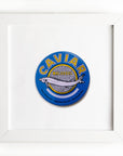 A framed graphic of a caviar tin label, featuring a blue and yellow design with an illustration of a sturgeon and the text "Caviar Malossol" on it, displayed against a white Match South Art Square White Frame background.