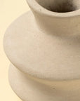 Close-up of the Indaba Wave Paper Mache Bud Vase—a light beige, handcrafted piece with a wide body and narrow neck. Set against a soft cream background, it showcases its smooth matte finish and sustainable design for elegant home decor.