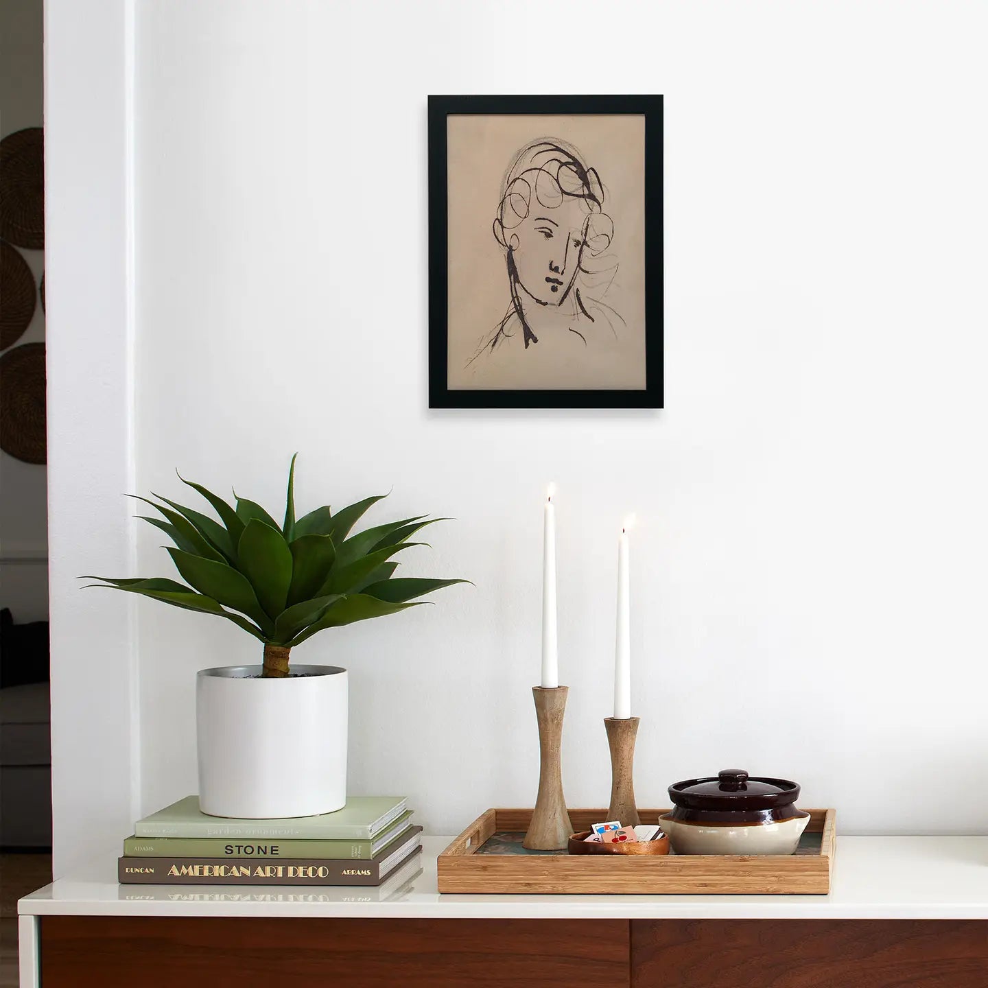 A minimal room includes a potted plant on books, two lit candles, a tray with a bowl, and "Haydon; Portrait study" by Faire—limited-edition art on matte paper in a simple frame displayed above.