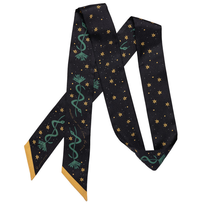 The Faire Twilly Scarf features black silk with yellow star patterns, green caduceus symbols, and yellow-tipped ends—arranged in a zigzag shape, it's an ideal gift for any occasion.