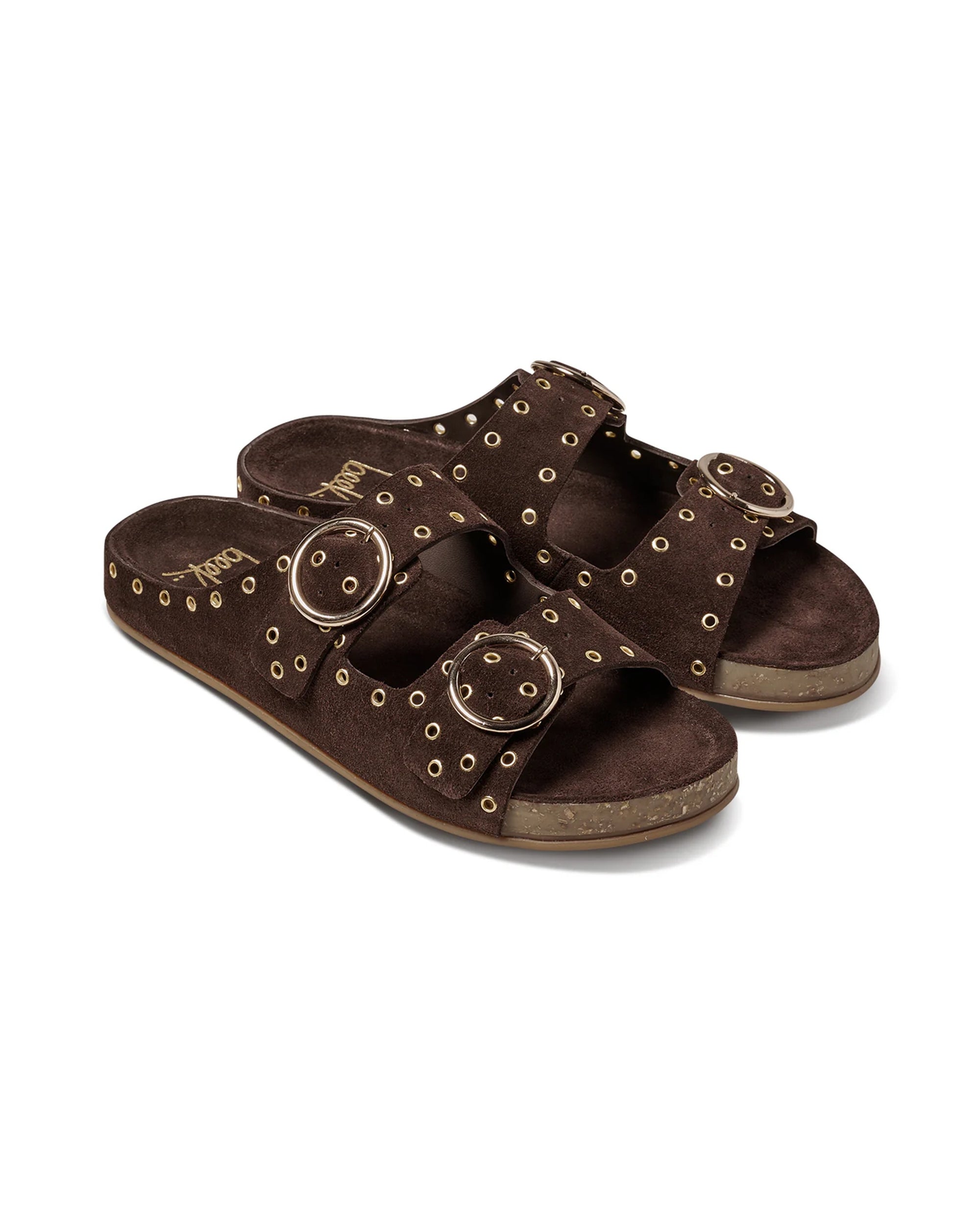 The Beek CEDAR is a dark brown suede slide sandal with two adjustable straps, large gold buckles, gold stud accents, a cork sole, and a memory foam footbed for extra comfort.