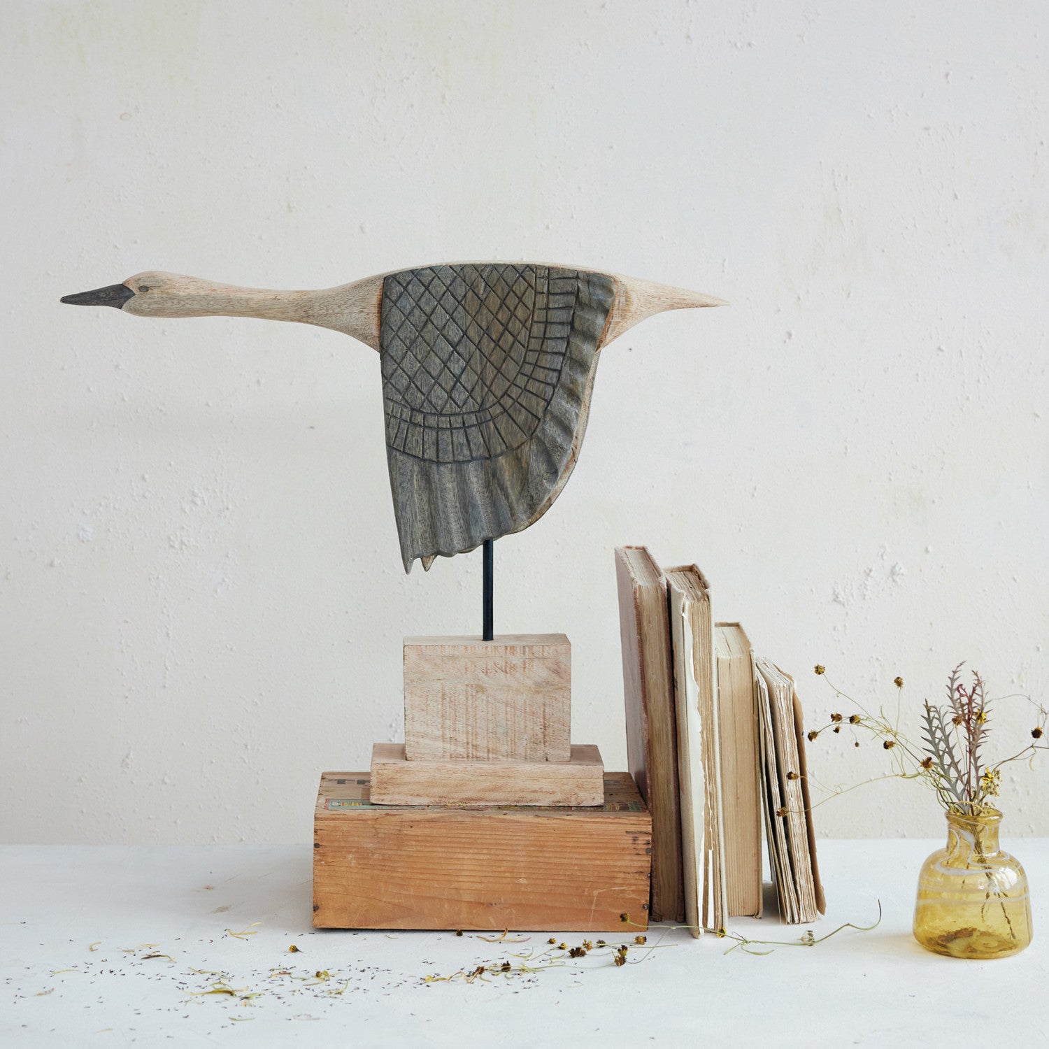 Goose sculpture by Creative Co-op displayed on a stand with vintage books and yellow dried flowers for a cozy accent.
