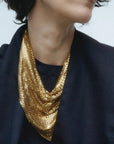 A person in a dark top wears the Faire Chain Mail Bandana Scarf Necklace draped stylishly around their neck. Their face is partially out of frame.