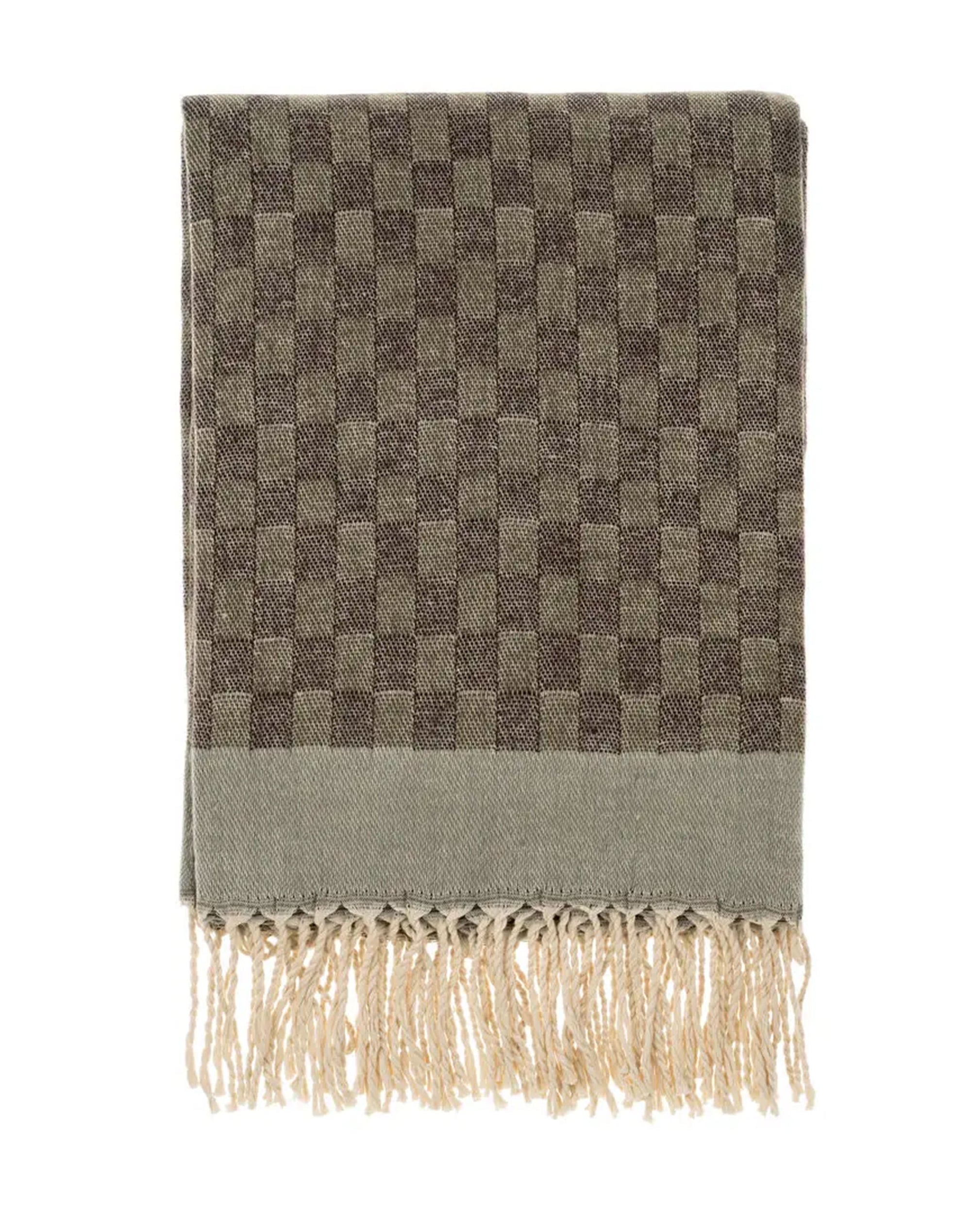 The Indaba Checkered Jacquard Throw in Dusk features a folded brown and beige check pattern with fringed tassels, shown on a white background.