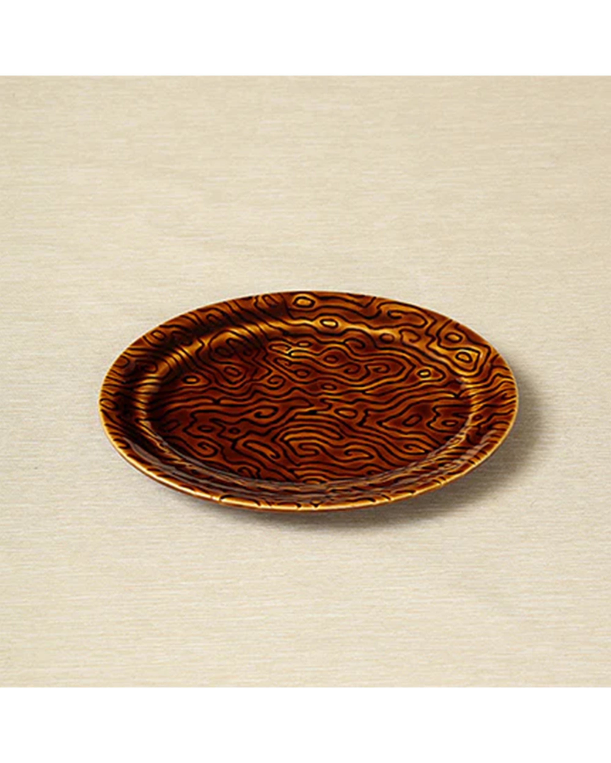 The TOB Aero Chesa Medium Plate is a round, shallow plate with a glossy brown surface and intricate vine motif in lighter shades, elegantly displayed on a neutral beige background.