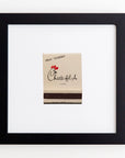 A framed Match South "Treat Yourself" gift card mounted on a white wall. The card features the Chick-fil-A logo and a small red heart above the acrylic text.