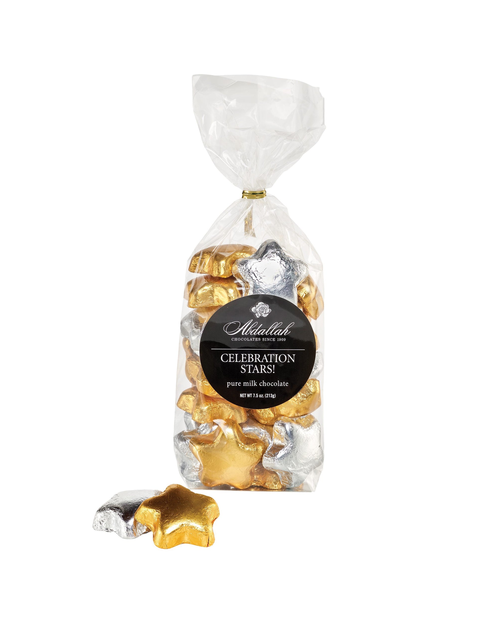 A clear bag of Abdallah MK Choc Celebration Star 7.5oz features gold and silver foiled milk chocolate star-shaped treats, with two chocolates displayed in front of the bag.
