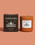 A brown box and matching candle jar with white "Nopalera" and "Ibarra" labels are shown on a light brown background. The Faire Nopalera Chocolate Candle is a limited edition inspired by the rich scent of Ibarra chocolate.
